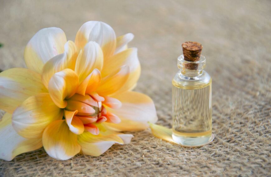 close up photo of white and yellow flower near glass bottle