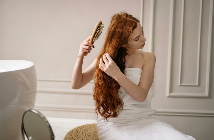 woman in white bath towel holding brown hair brush